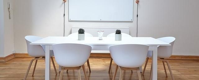 Konferenzraum mit sechs weißen Stühlen um einen Tisch